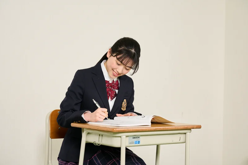 ノートに書き込みながら勉強する高校生