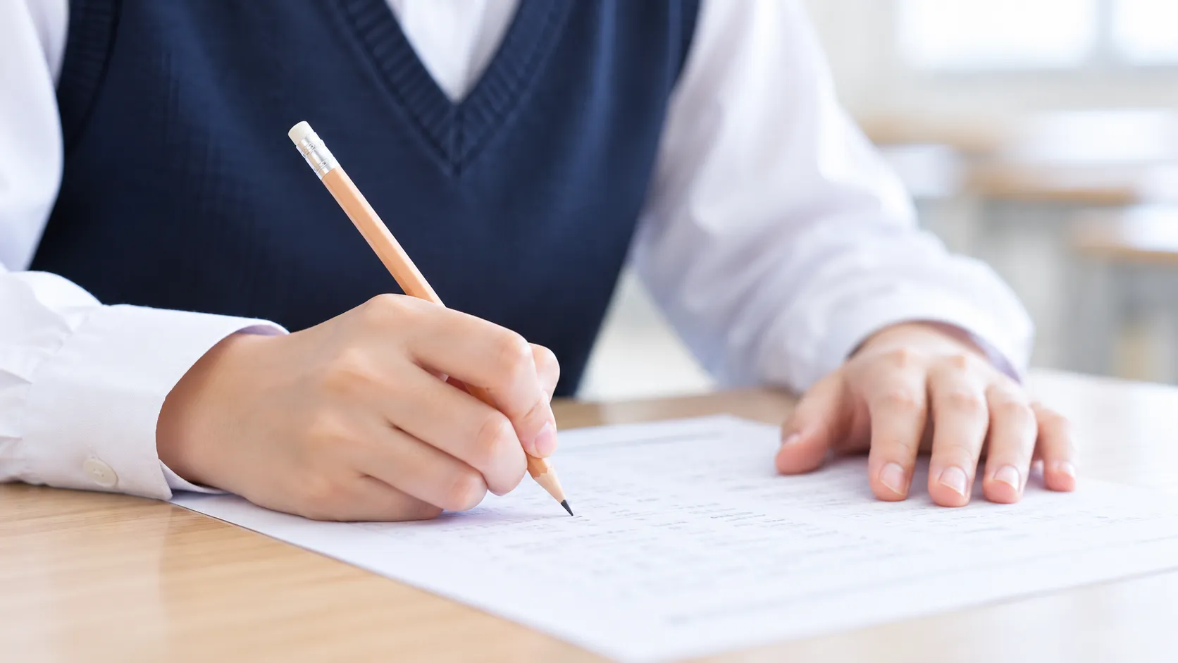 問題用紙に向かって答えを書き込む中学生